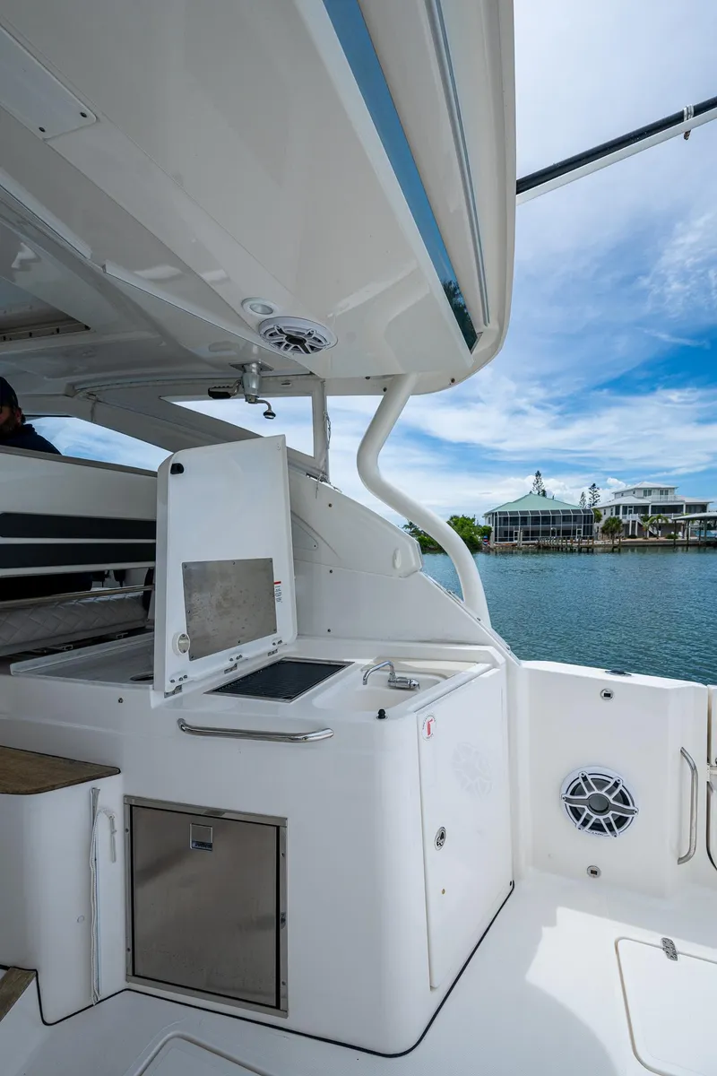 Slide: The Image of 2023 Pursuit DC 365 Dual Console boat interior with open storage, dockside view. - 28