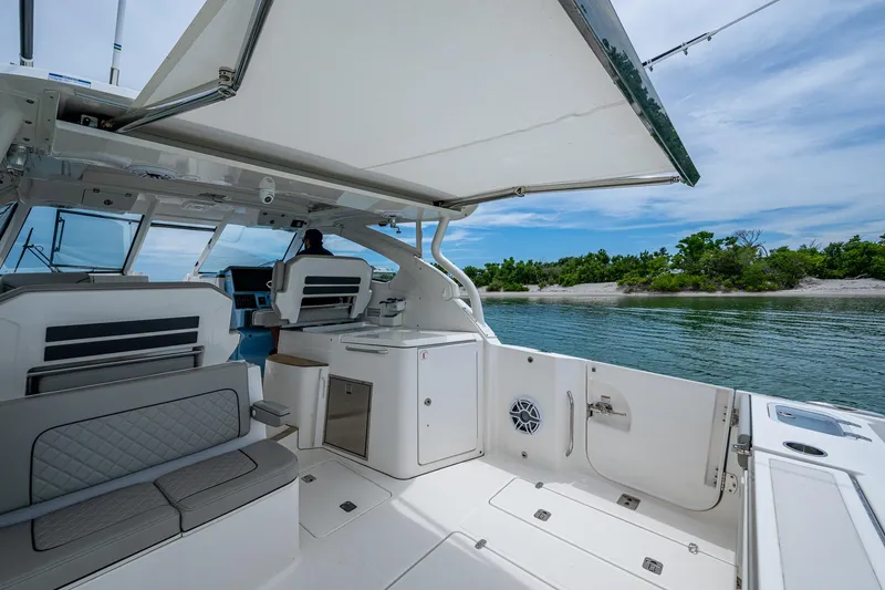 Slide: The Image of 2023 Pursuit DC 365 Dual Console boat interior with seating, canopy, and water view. - 32