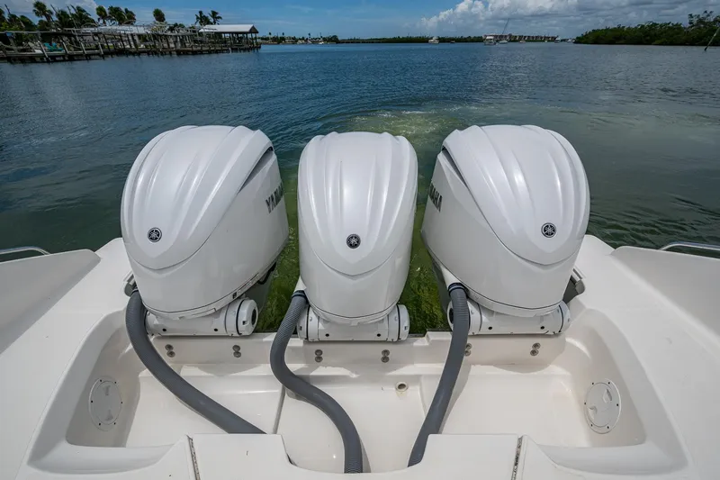 Slide: The Image of Triple Yamaha outboard engines on a 2023 Pursuit DC 365 Dual Console boat, docked on calm water. - 34