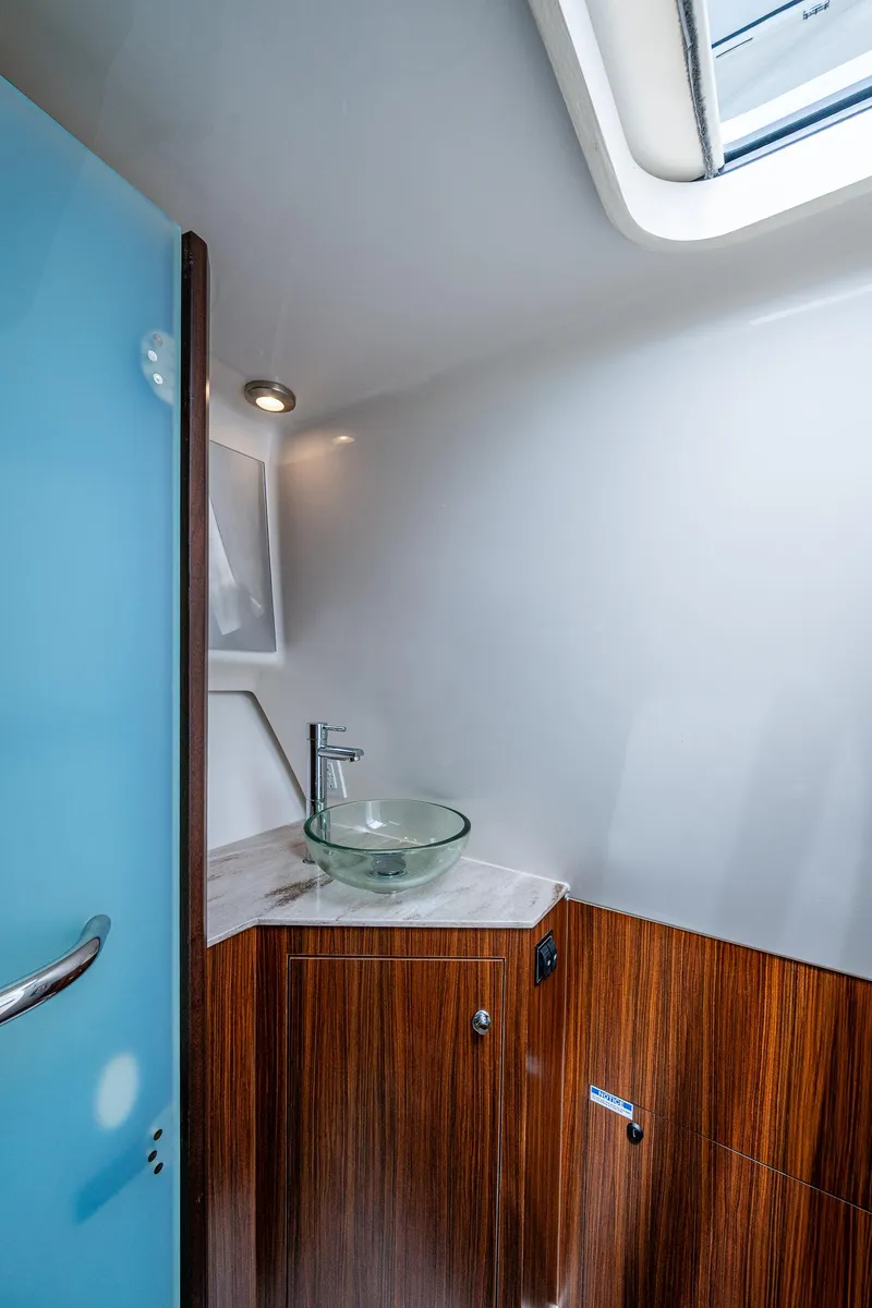 Slide: The Image of 2023 Pursuit DC 365 Dual Console boat interior with modern sink and wood finish. - 38