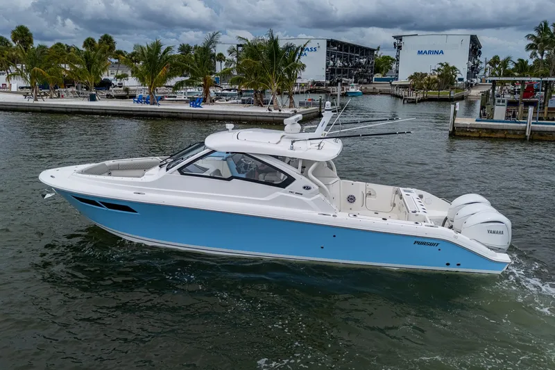 Slide: The Image of 2023 Pursuit DC 365 Dual Console boat cruising near marina with palm trees. - 6