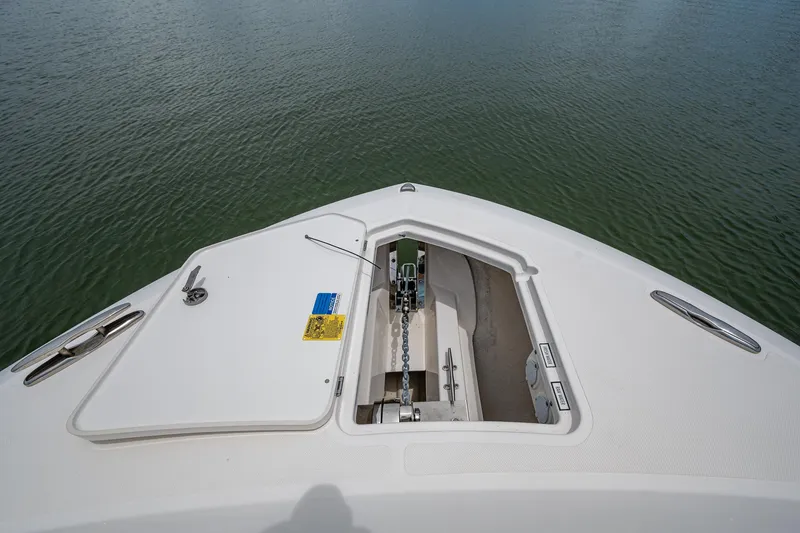 Slide: The Image of 2023 Pursuit DC 365 Dual Console boat anchor compartment on calm water. - 8