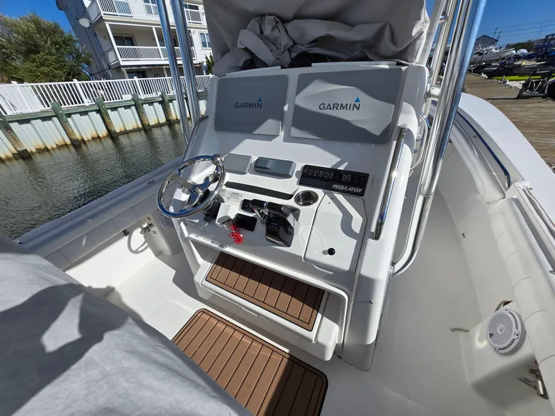 Slide: The Image of 2017 Regulator 28 boat console with Garmin displays and steering wheel, docked by waterfront. - 20