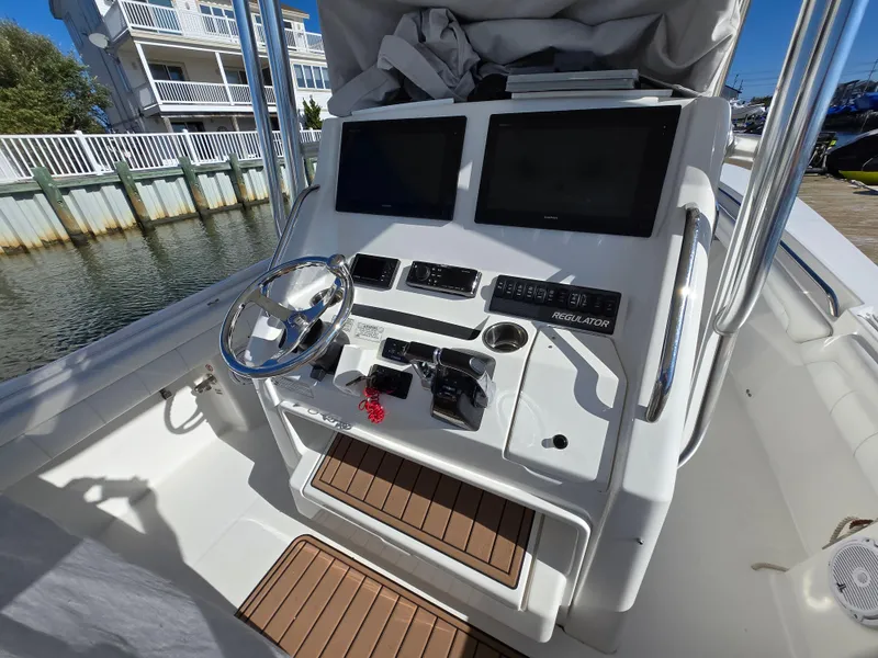 Slide: The Image of 2017 Regulator 28 boat console with dual screens and steering wheel, dockside view. - 21