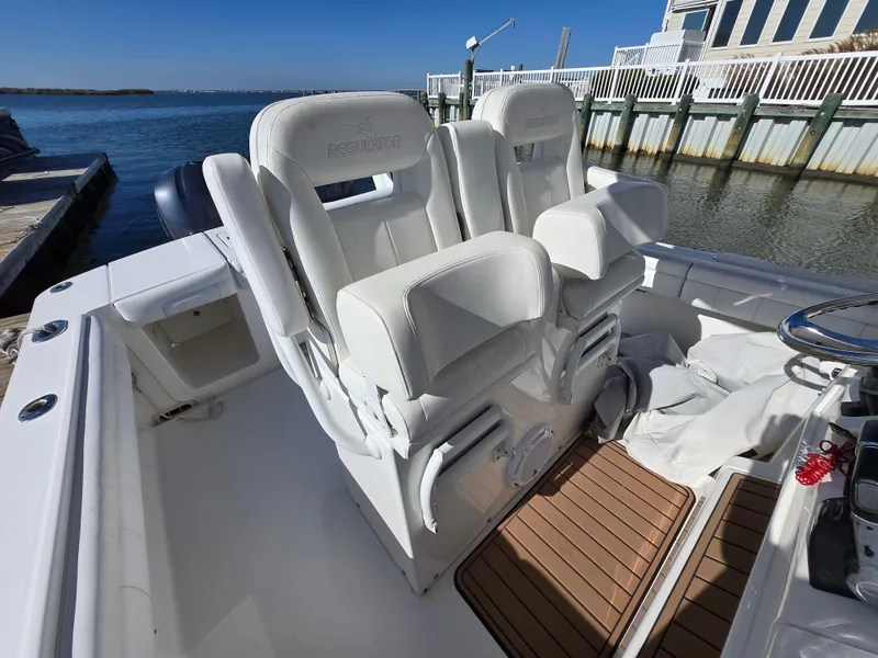 Slide: The Image of 2017 Regulator 28 boat interior with white seating and wooden flooring by the dock. - 25