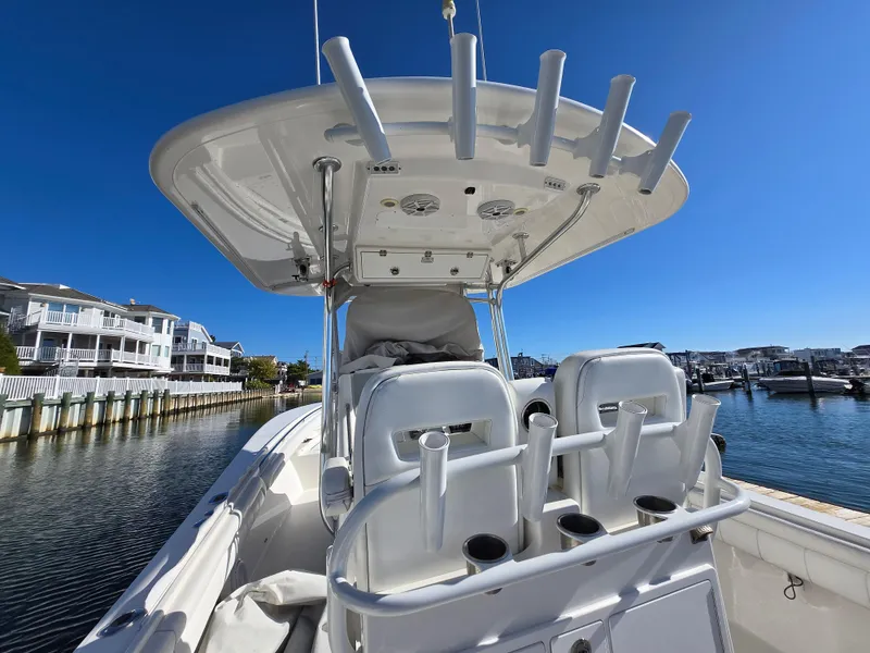 Slide: The Image of 2017 Regulator 28 boat with rod holders, docked near waterfront homes under clear blue sky. - 28