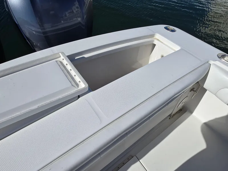 Slide: The Image of 2017 Regulator 28 boat interior with storage compartment and seating, docked on water. - 34