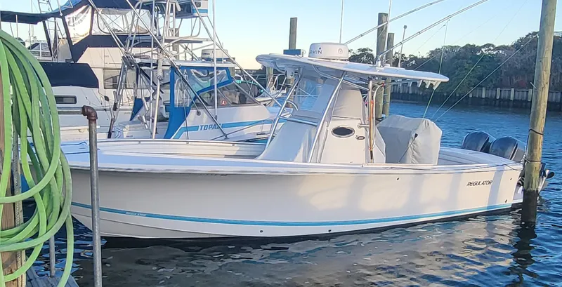 Slide: The Image of 2017 Regulator 28 boat docked at marina, side view with clear sky background. - 6
