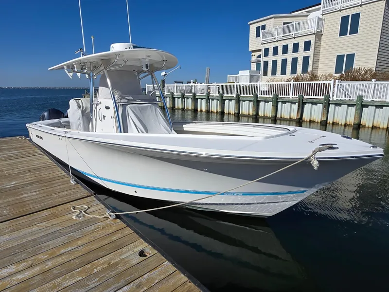 Slide: The Image of 2017 Regulator 28 boat docked by waterfront homes under clear blue sky. - 7
