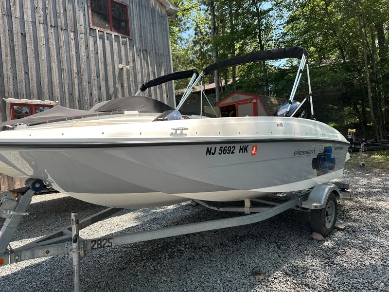 The Image of 2019 Bayliner Element E16 boat on trailer, parked near rustic building. - 1