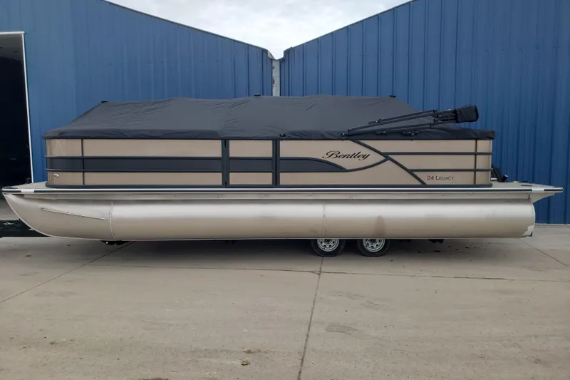 Slide: The Image of 2026 Bentley Pontoons Legacy 243 Cruise pontoon boat with cover, parked by blue building. - 5