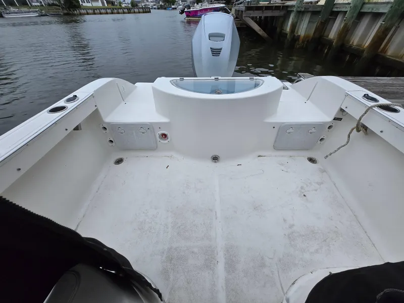 Slide: The Image of 2010 Sea Fox 216 Walk Around boat interior with motor, docked by the water. - 10