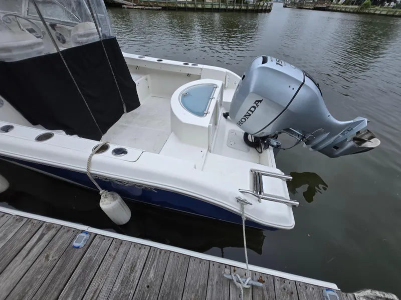 Slide: The Image of 2010 Sea Fox 216 Walk Around boat with Honda outboard motor docked by the water. - 4