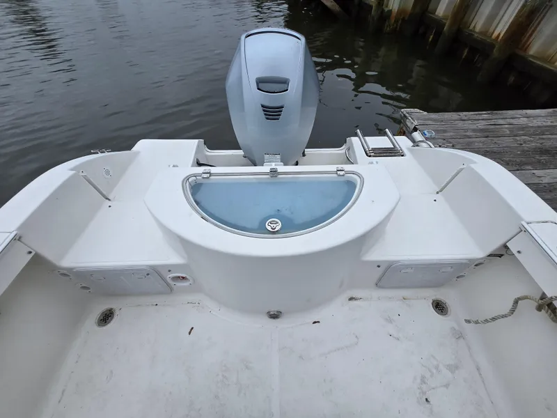 Slide: The Image of 2010 Sea Fox 216 Walk Around boat stern with motor and livewell, docked by water. - 5