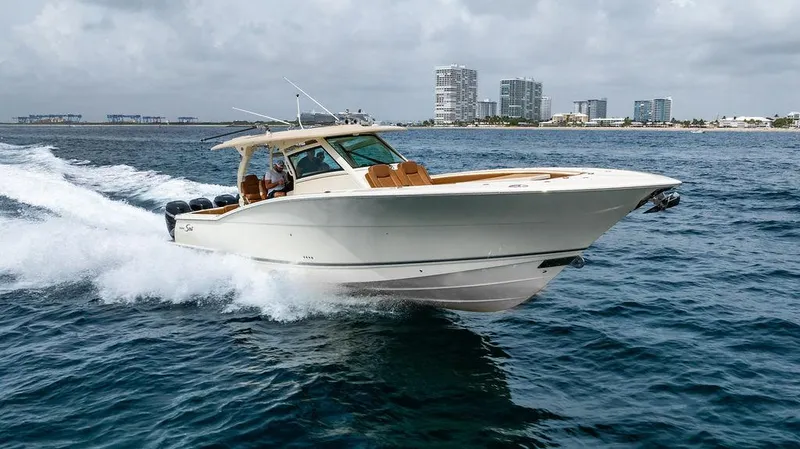 The Image of 2018 Scout 420 LXF boat cruising on ocean near city skyline. - 0