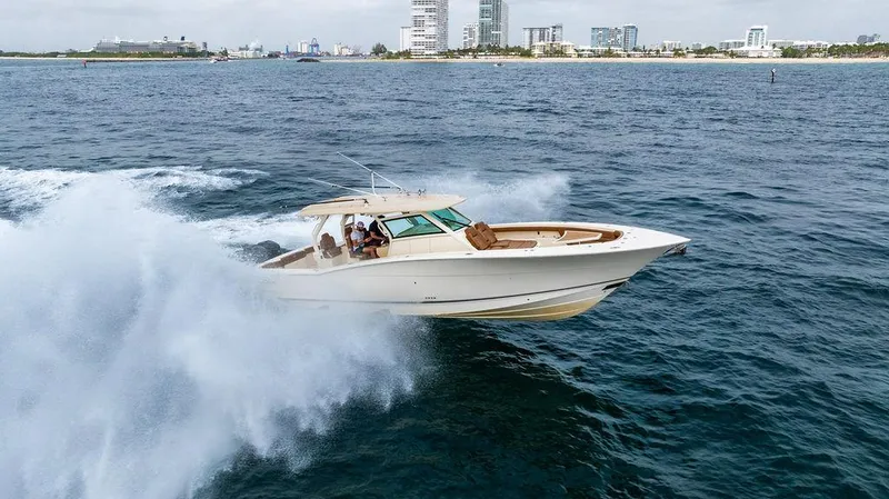 Slide: The Image of 2018 Scout 420 LXF boat cruising on open water near city skyline. - 11