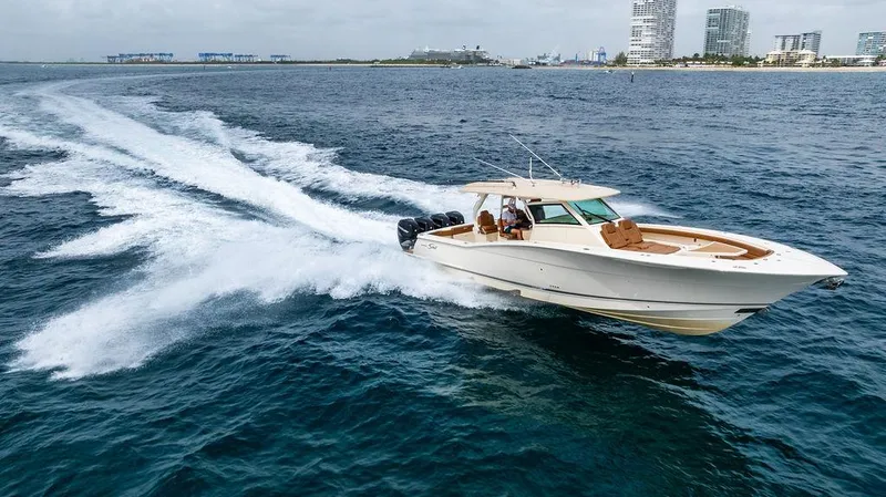 Slide: The Image of 2018 Scout 420 LXF boat cruising on open water near city skyline. - 12