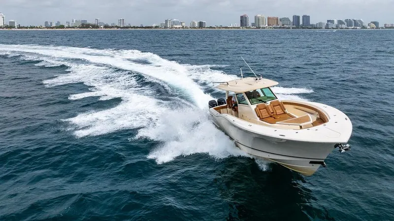 Slide: The Image of 2018 Scout 420 LXF boat cruising on ocean near city skyline. - 15