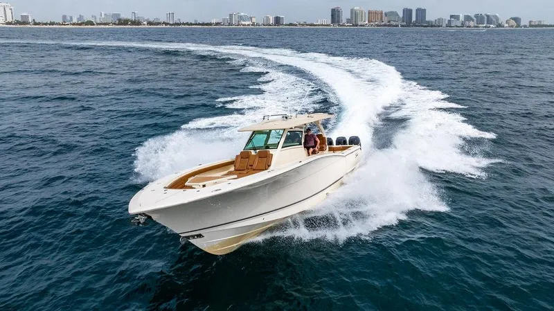 Slide: The Image of 2018 Scout 420 LXF boat cruising on open water near a city skyline. - 16