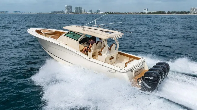 Slide: The Image of 2018 Scout 420 LXF boat cruising on open water with multiple Mercury engines. - 19