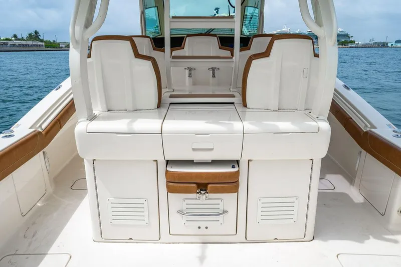 Slide: The Image of 2018 Scout 420 LXF boat interior with seating and storage, docked by the water. - 47