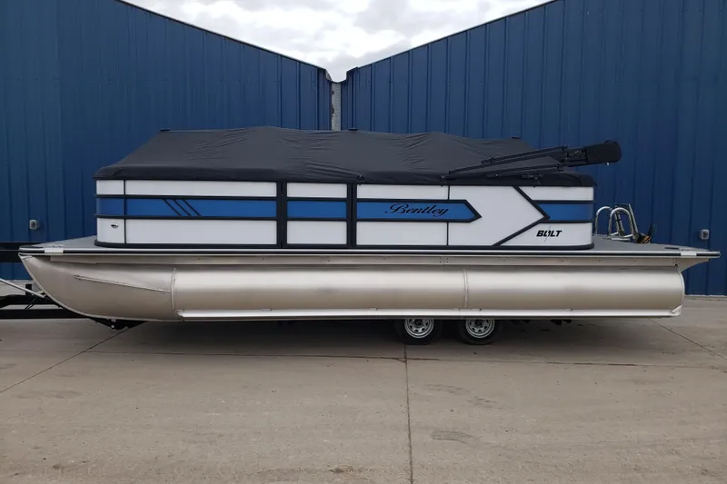 Slide: The Image of 2026 Bentley Pontoons 223 Bolt, covered, parked on concrete, blue and white design. - 5
