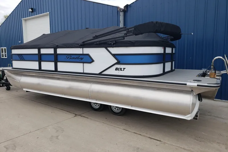 Slide: The Image of 2026 Bentley Pontoons 223 Bolt, covered, parked by a blue building. - 6