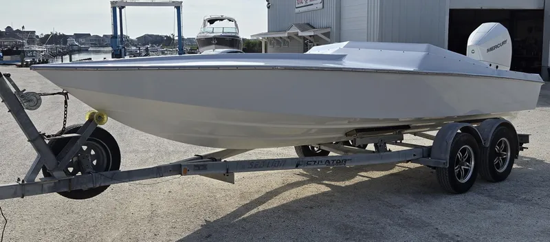 Slide: The Image of 1991 Activator 22 speedboat on trailer, parked outdoors near marina. - 11