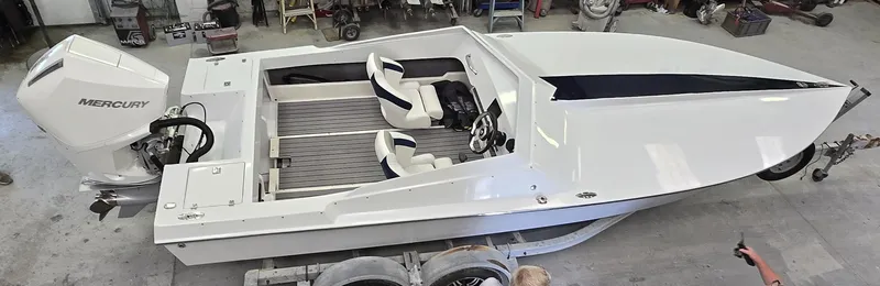 Slide: The Image of White 1991 Activator 22 speedboat with Mercury engine, parked in a garage on a trailer. - 14