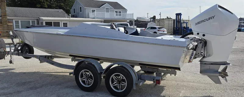 Slide: The Image of 1991 Activator 22 boat on trailer with Mercury outboard motor, parked near houses. - 4