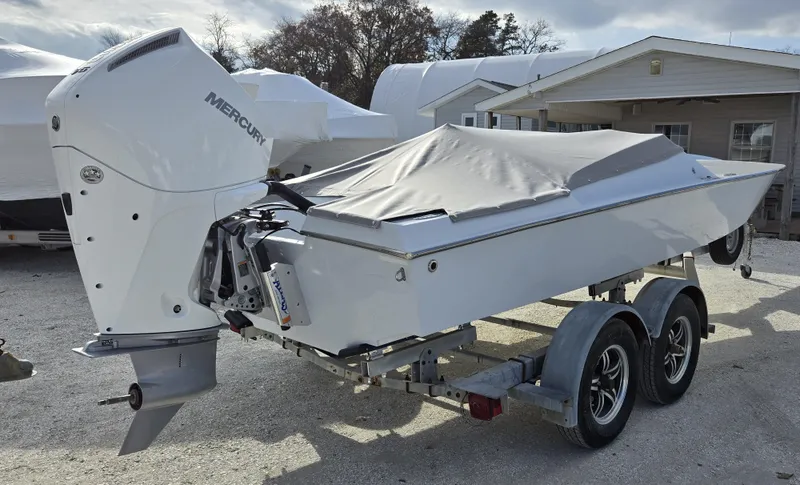 Slide: The Image of 1991 Activator 22 boat on trailer with Mercury outboard engine, covered and parked outdoors. - 7