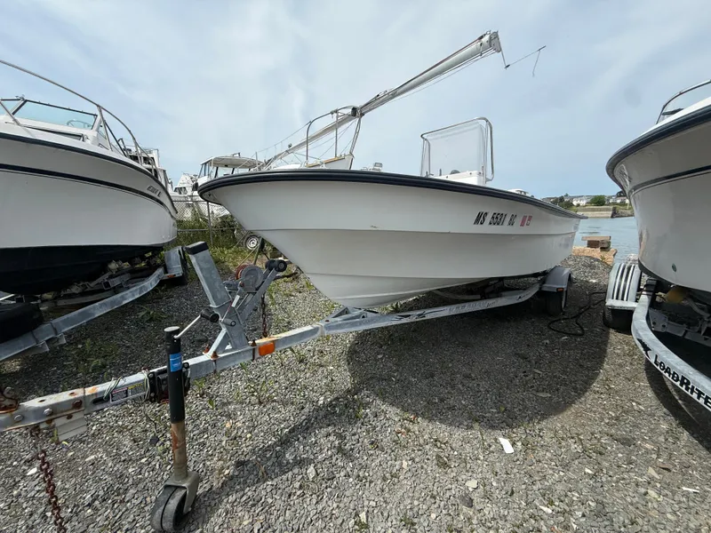 Slide: The Image of 2002 Maritime Skiff 1890 boat on trailer, parked between other boats, gravel ground. - 3