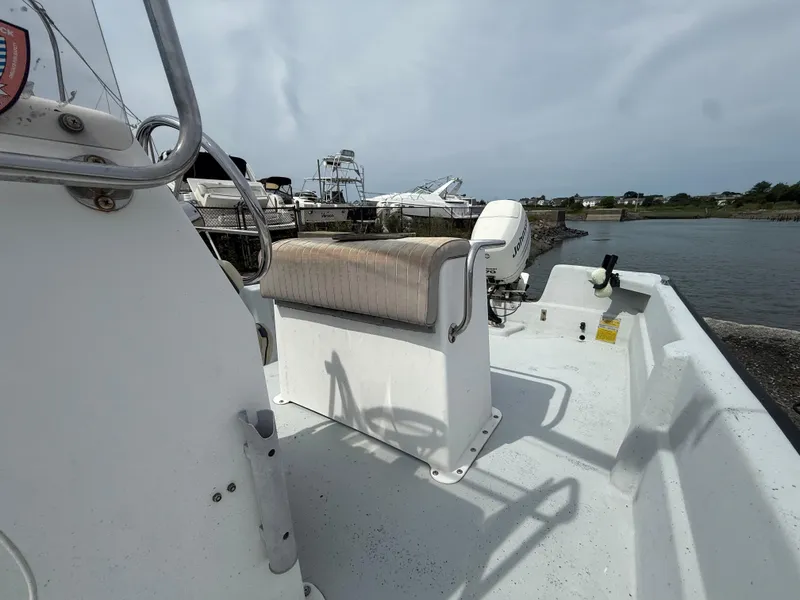 Slide: The Image of 2002 Maritime Skiff 1890 boat interior with seating and outboard motor by the water. - 7