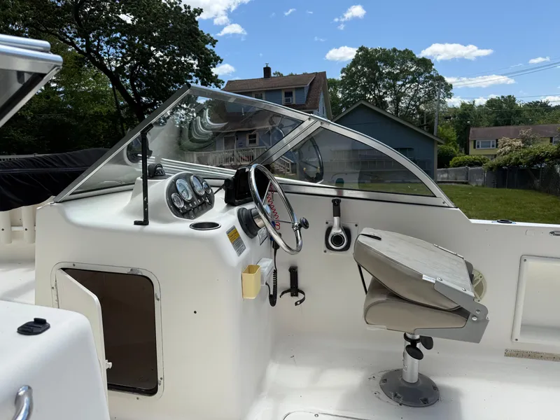 Slide: The Image of 2005 Sea Hunt Escape 200 boat cockpit with steering wheel and gauges, parked outdoors. - 13