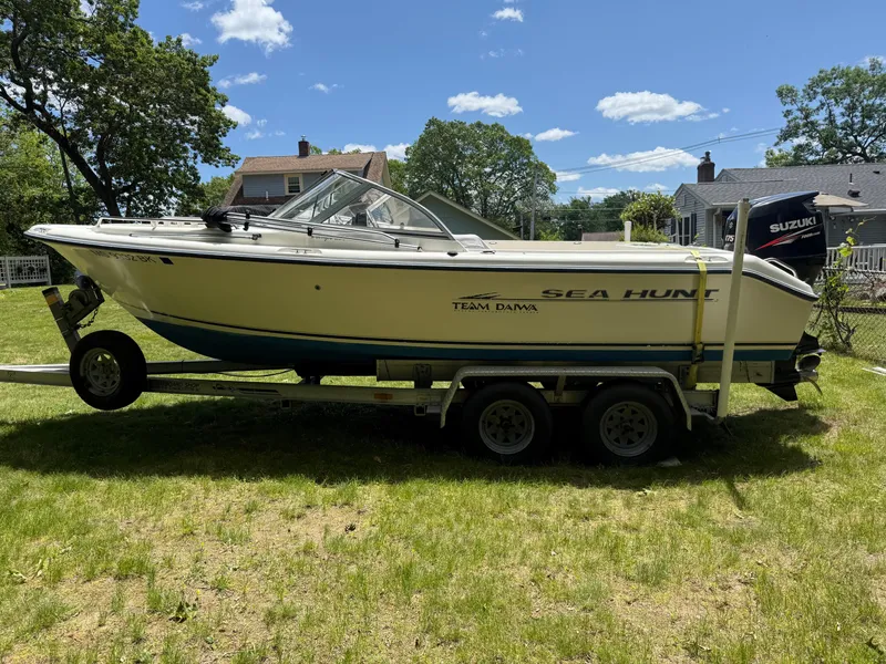 Slide: The Image of 2005 Sea Hunt Escape 200 boat on trailer, parked on grass under a clear blue sky. - 2