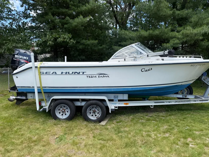 Slide: The Image of 2005 Sea Hunt Escape 200 boat on trailer, parked on grass, with Suzuki outboard motor. - 3