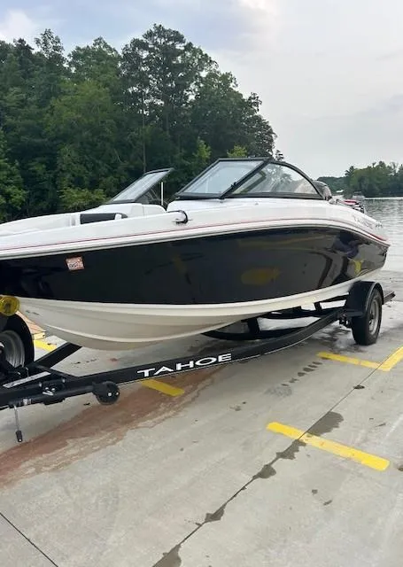 Slide: The Image of 2023 Tahoe 185 S boat on trailer, parked near a lake with trees in the background. - 7