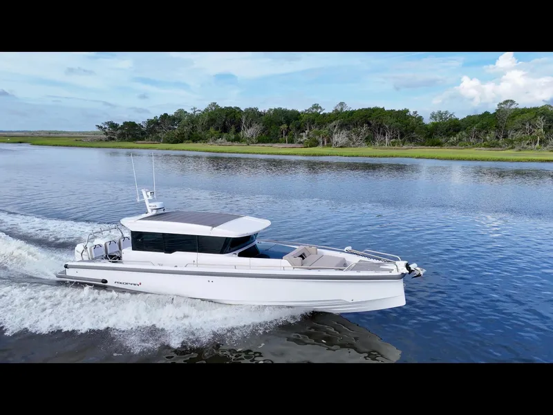 The Image of 2023 Axopar 37 Cross Cabin cruising on a serene river with lush green shoreline. - 0