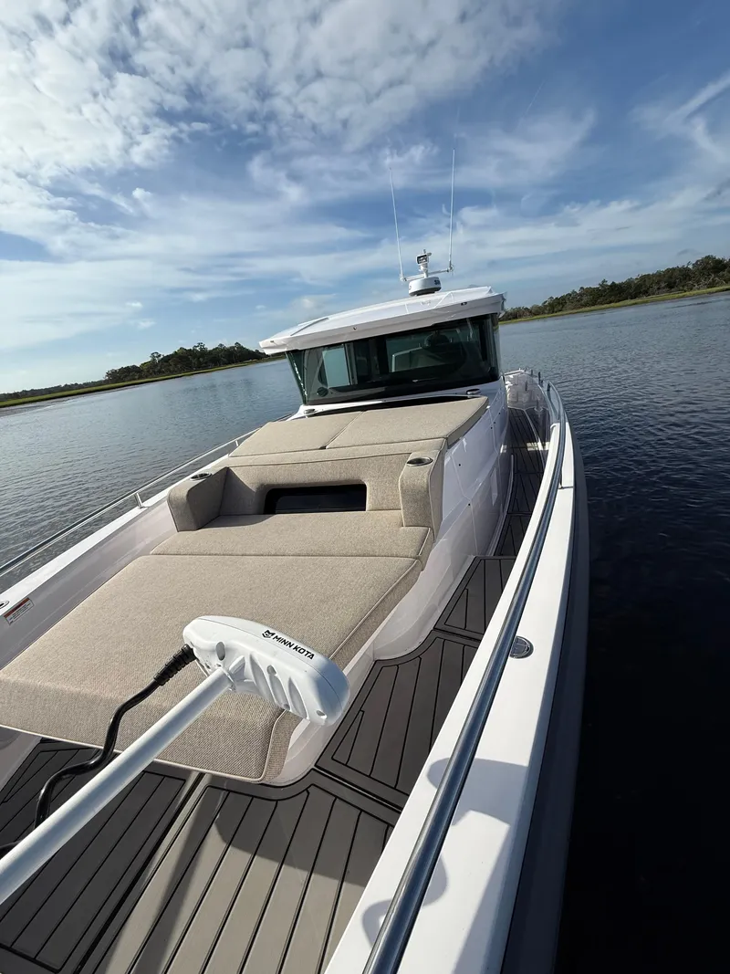 Slide: The Image of 2023 Axopar 37 Cross Cabin boat on calm water under a blue sky. - 10