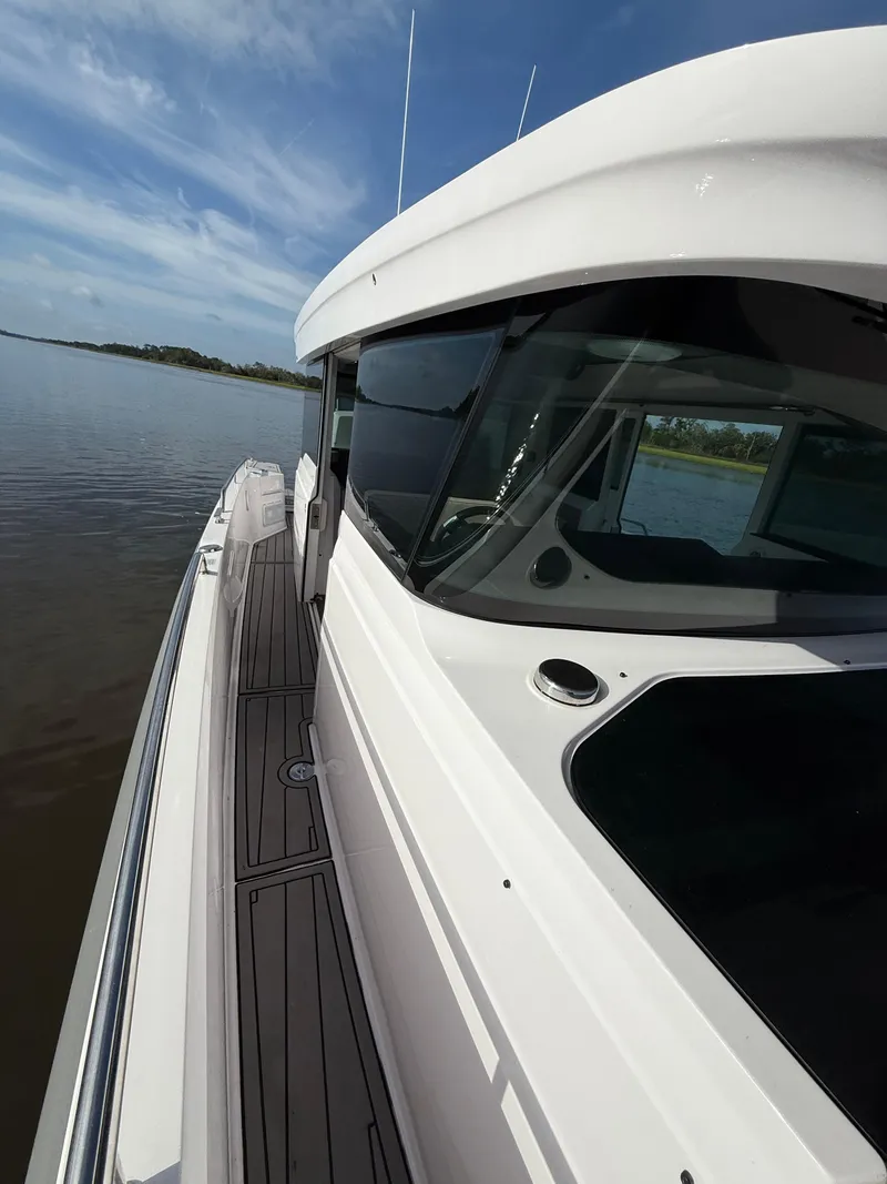 Slide: The Image of 2023 Axopar 37 Cross Cabin boat on calm water, showcasing sleek design and modern features. - 11