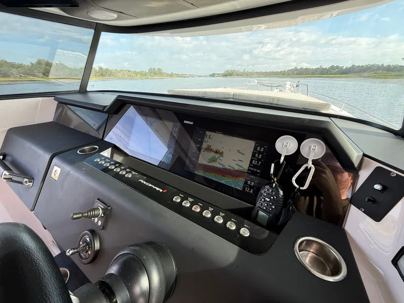 Slide: The Image of 2023 Axopar 37 Cross Cabin dashboard with navigation system and scenic waterway view. - 15