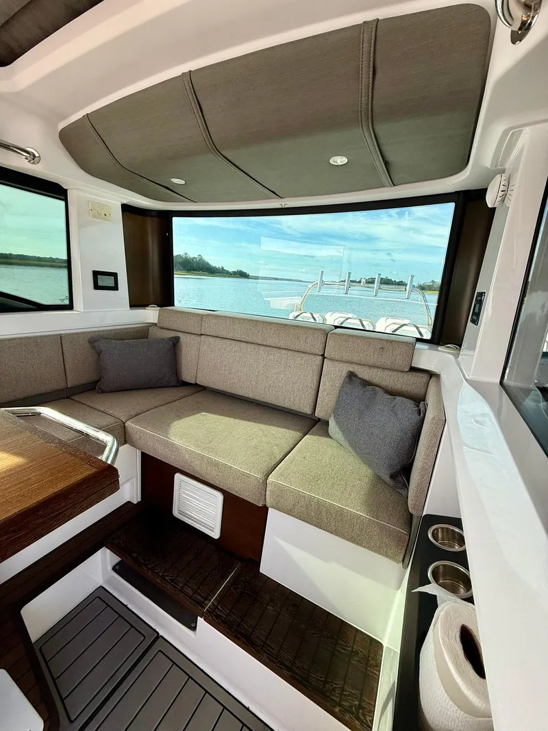 Slide: The Image of Interior of 2023 Axopar 37 Cross Cabin with cozy seating and scenic window view. - 18