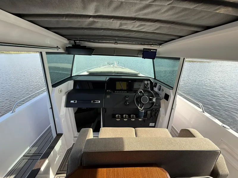 Slide: The Image of 2023 Axopar 37 Cross Cabin interior with modern helm and panoramic water view. - 23