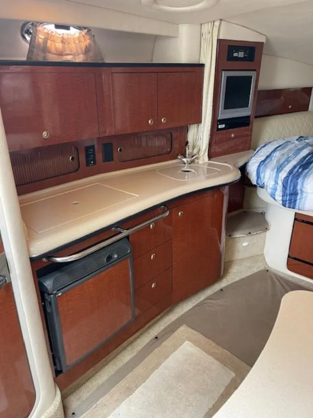 Slide: The Image of Interior of 2004 Sea Ray 320 Sundancer yacht with kitchenette and cozy sleeping area. - 13
