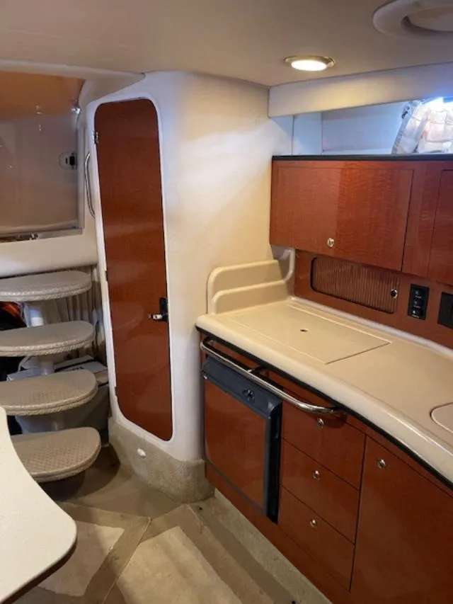 Slide: The Image of Interior of 2004 Sea Ray 320 Sundancer yacht, featuring a compact kitchen and staircase. - 14