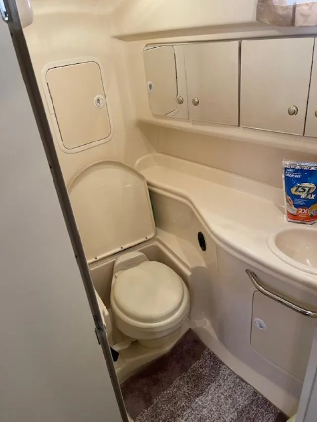 Slide: The Image of 2004 Sea Ray 320 Sundancer bathroom with toilet, sink, and storage cabinets. - 15