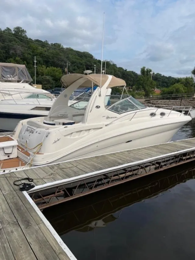 Slide: The Image of 2004 Sea Ray 320 Sundancer docked at a marina, surrounded by lush greenery. - 16