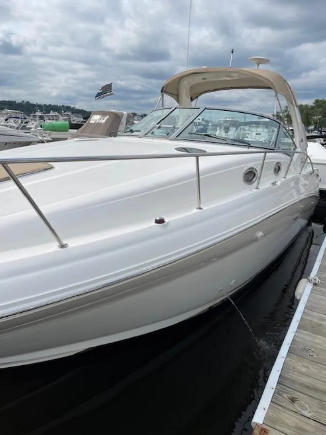 Slide: The Image of 2004 Sea Ray 320 Sundancer docked, showcasing sleek design and spacious deck under cloudy skies. - 18