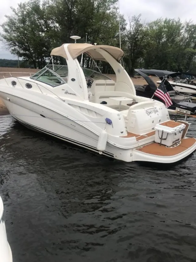 Slide: The Image of 2004 Sea Ray 320 Sundancer boat docked on calm water with American flag. - 2
