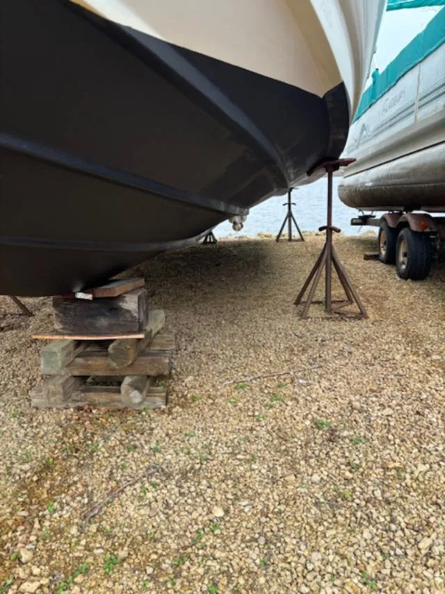 Slide: The Image of 2004 Sea Ray 320 Sundancer on dry dock, supported by wooden blocks and stands. - 20